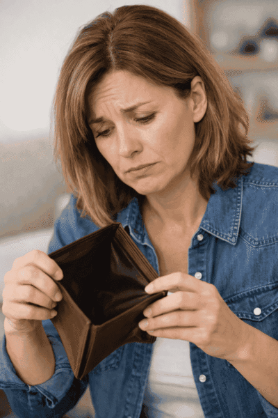 une femme en train de regarder son portefeuille vide